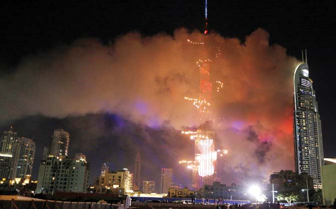 Fireworks at Burj Khalifa while smoke billows from the Address Downtown Hotel on New Year’s Eve. Pics/AFP
