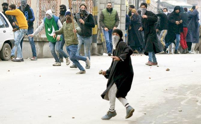 Different reasons, different protests : Kashmiri protestors throw stones towards police as teargas smoke drifts across a road during clashes in Srinagar on January 8, 2016. Police fired dozens of teargas shells and rubber bullets to disperse Kashmiri Muslims protesting against Indian rule. Pic/AFP