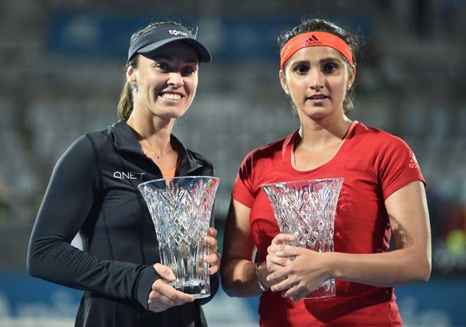 Martina Hingis of Switzerland (L) and Sania Mirza of India (R) hold the winners trophies after beating Caroline Garcia and Kristina Mladenovic of France in the women
