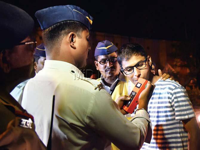 A traffic constable performs the breath analyser test on a reveller in Juhu on New Year’s Eve. Pic/Nimesh Dave