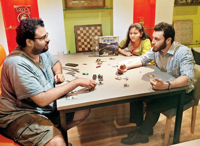 (L-R) Aniceto Pereira, Riddhi Dalal and Mohsin Memon play X-Wing Miniature, The Force Awakens at Creeda Board Game Café at Fort