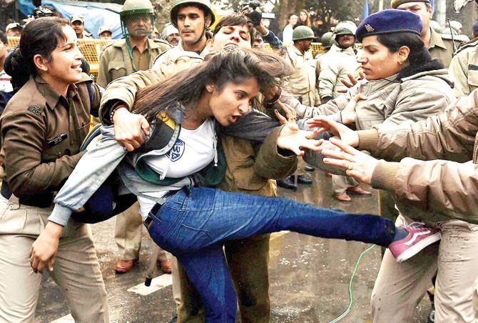 Take that: A student kicks a police official, who was trying to detain her, while protesting against the Ministry of Human Resource Development in New Delhi yesterday over the suicide of a PhD scholar  Rohith Vemula at University of Hyderabad. Pic/PTI 