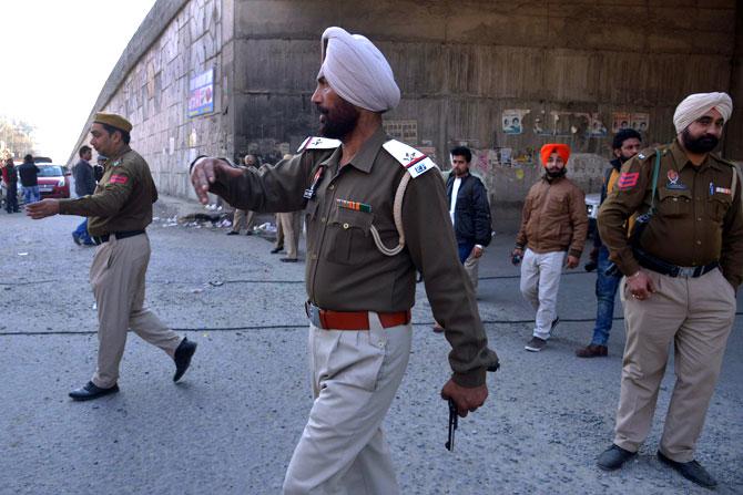Police personnel clear bystanders on a road leading to an airforce base in Pathankot. AFP PHOTO