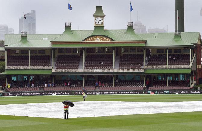 Security personnel stand guard as rain delays play on the third day