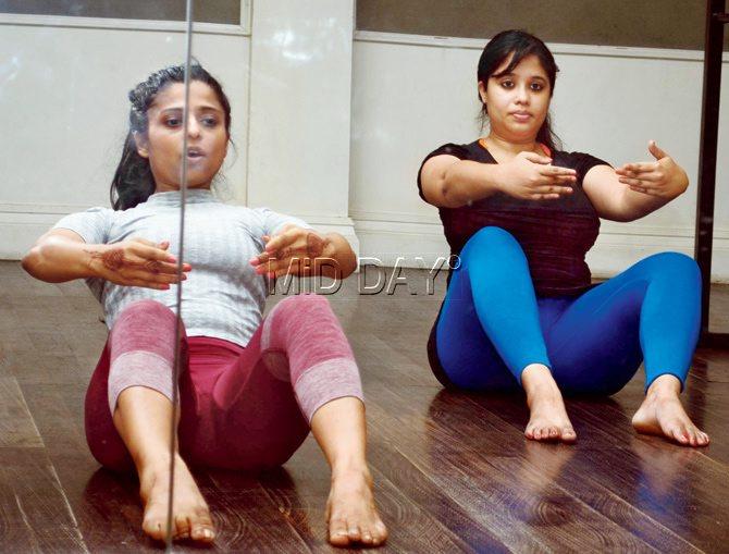 (Left) Indiana Mehta and the reporter (right) with legs in front in bow position. We raise our hands in a Port de bras, [ballet arms] position and combine it with an abs workout 