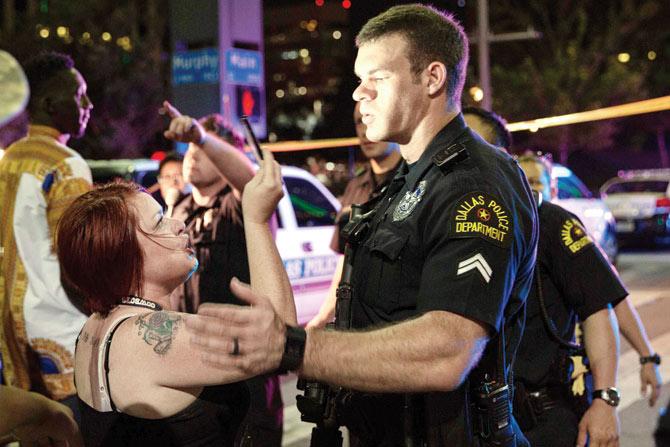 A cop tries to calm protestors after the sniper shooting in Dallas. Pic/AFP