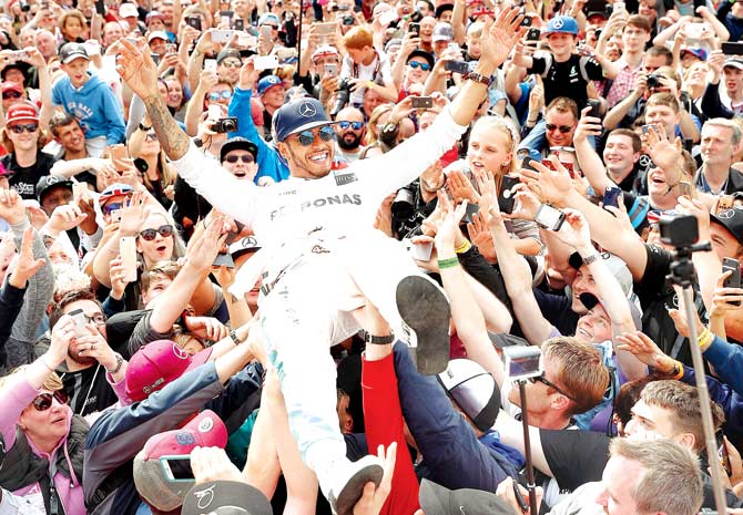 A delighted Lewis Hamilton celebrates his British Grand Prix win by performing a crowd surf with supporters at Silverstone, UK, yesterday. Pic/Getty Images