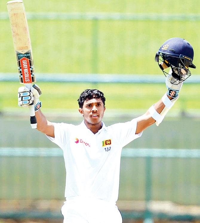 Kusal Mendis raises his bat and helmet in celebration after scoring a century (100 runs) during the third day of their opening Test match between Sri Lanka and Australia at the Pallekele International Cricket Stadium in Pallekele. Pic/AFP