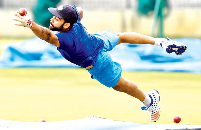 India Test skipper Virat Kohli dives to take a catch during a practice session at the National Cricket Academy in Bangalore yesterday. Pic/AFP