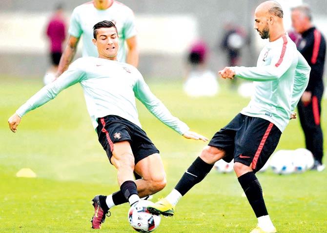 Portugal striker Cristiano Ronaldo (left) is tackled by teammate Ricardo Quaresma during a training session in Marcoussis, near Paris on the eve of their Euro 2016 semi-final against Wales in Lyon tonight. Pics/Getty Images