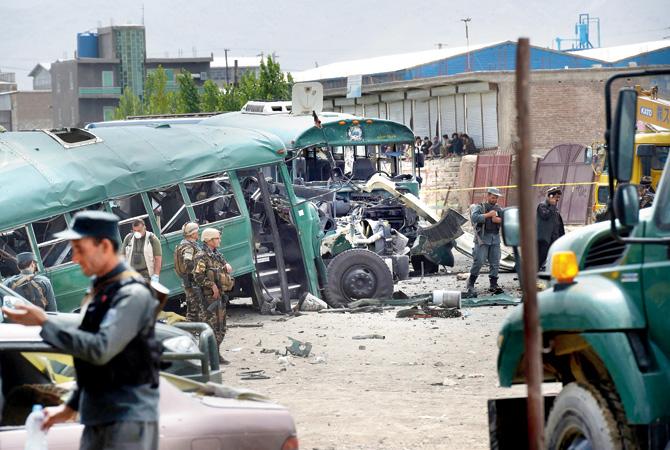 Afghan security personnel gather near the wreckage of buses which were carrying police cadets at the site of a bomb attack on the outskirts of Kabul yesterday. Pic/AFP