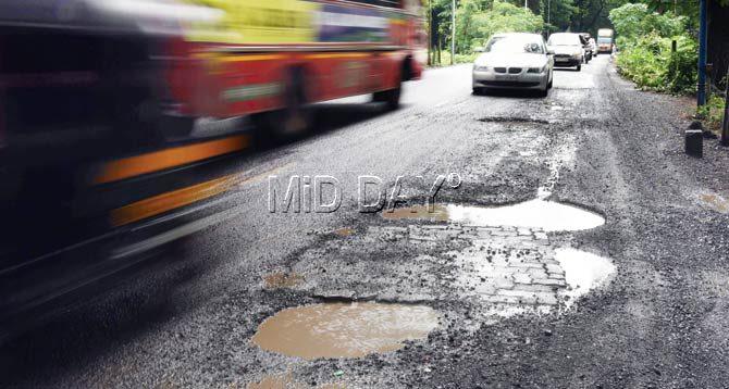 A car driver braces for a bumpy ride on an arterial road of Aarey Milk Colony. Pic/Nimesh Dave