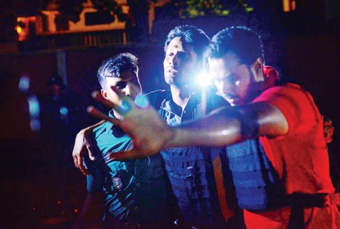 A Bangladeshi policeman injured in the attack is helped outside the Holey Artisan Bakery cafe. Pic/AFP