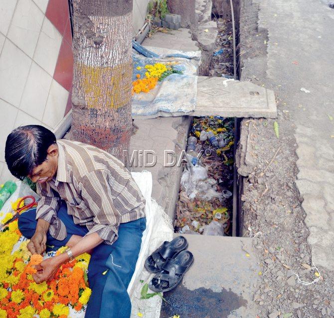 A flower vendor sets up shop right next to an open drain in Bhandup
