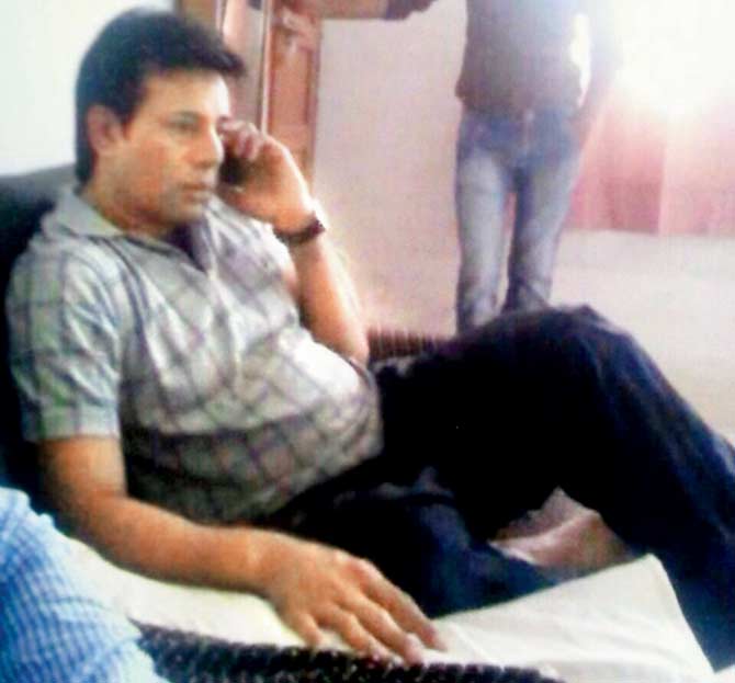 Abu Salem chats on a mobile phone at the waiting room of the Lucknow railway station while under police scrutiny