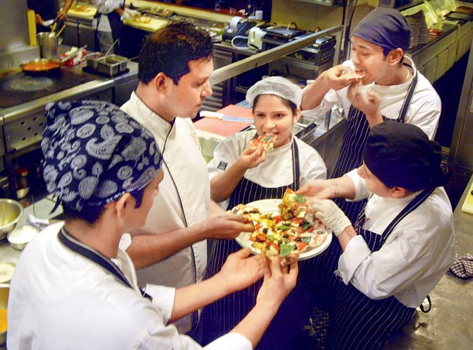 (From left) Interns Jay Wadhwaniya, Rohit Vishwakarma and Priyanka Tandon bite into freshly-made pizza with chefs Donald Fernandes and Pooja Bhagwat (second and third from left) at an Indigo Deli outpost. Pic/Sayyed Sameer Abedi