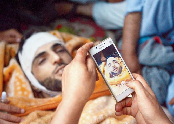 Kashmiri mourners take photographs of the body of Burhan Muzaffar Wani before his funeral at Tral near Srinagar. Pic/AFP