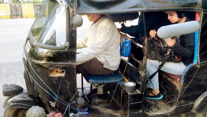 A crew member records the sound of an autorickshaw for the film