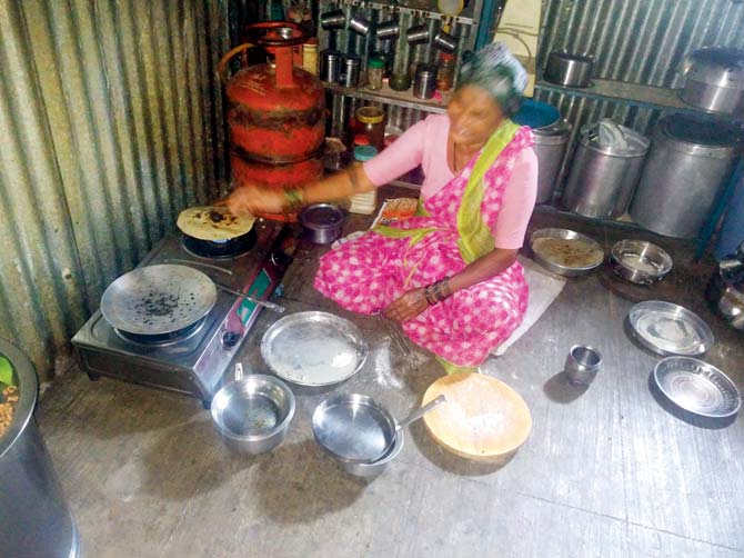 Ramchandra Zanjare’s wife cooking a meal inside the tin shed