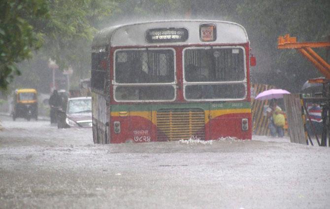 A BEST bus plys through a flooded road during heavy rains in Mumbai on Sunday. PTI