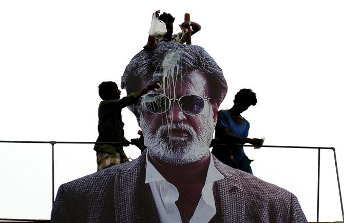 Fans pouring milk on a giant poster of actor Rajinikanth celebrating the release of 