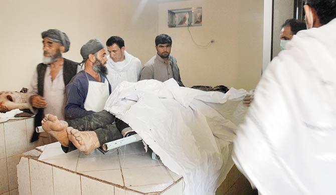 Relatives of a victim stand over his body in a hospital in Kunduz province of Afghanistan yesterday.