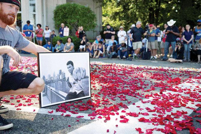 A fan holds a photograph of boxing legend Muhammad Ali as spectators wait for the arrival of Ali’s funeral procession to enter Cave Hill Cemetery, Kentucky yesterday. PICS: AP/PTI, AFP