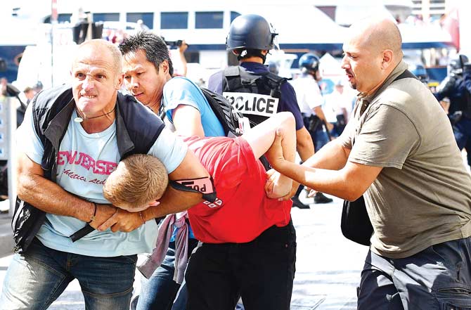 An England fan is restrained by police personnel in Marseille