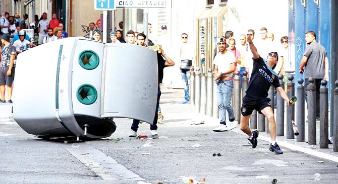 A man throws a bottle at English fans at a Marseille street