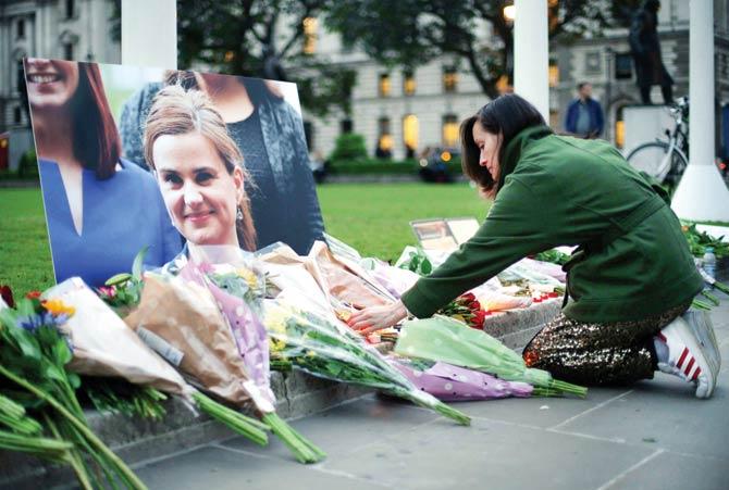 People place floral tributes and candles by a picture of slain Labour MP Jo Cox at a vigil in Parliament square in London yesterday. Pic/AFP