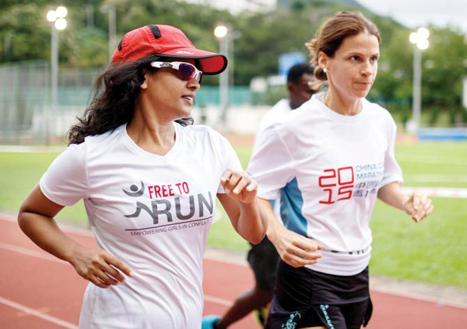Naina (L) runs on a running track with Virginie Goethals (R), in Hong Kong. Pic/AFP