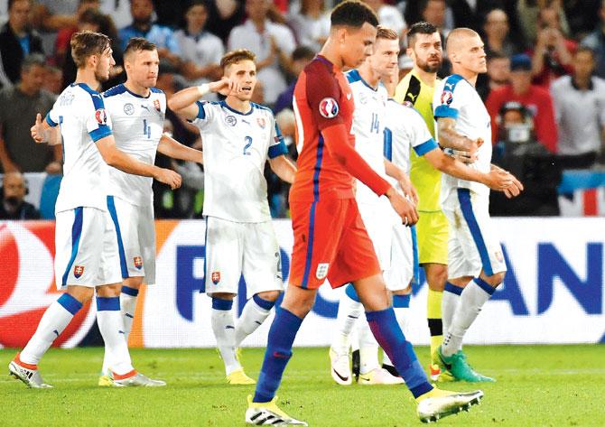 A dejected England midfielder Dele Alli (centre) walks past Slovakian players after the Euro 2016 match in Saint-Etienne on Monday. Pic/AFP