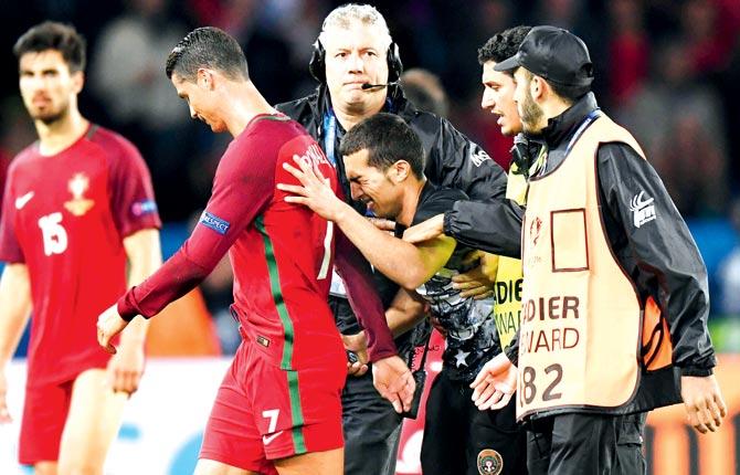 Stewards take a Portugal fan (centre) off the pitch as he attempts to reach Cristiano Ronaldo for a selfie during the Euro 2016 match vs Austria at the Parc des Princes in Paris, France. Pic/Getty Images