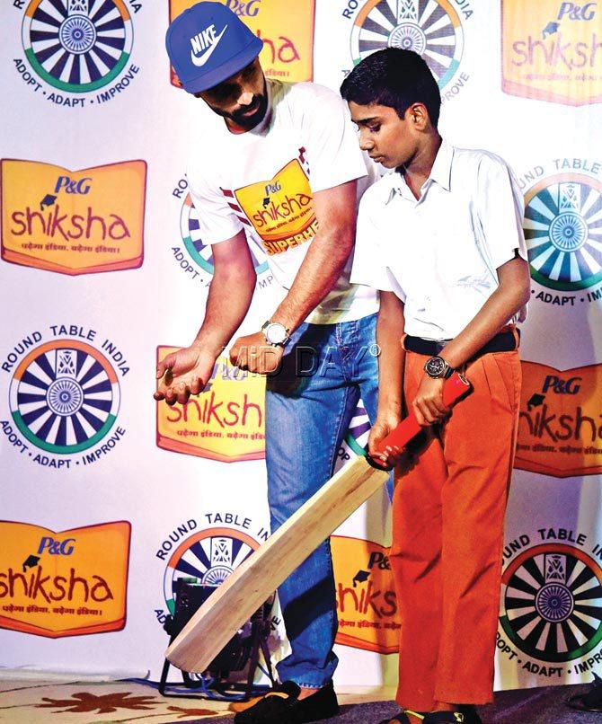 Bat, man: India batsman Ajinkya Rahane teaches a kid how to bat  during a promotional event at a city hotel yesterday. Pic/Atul Kamble