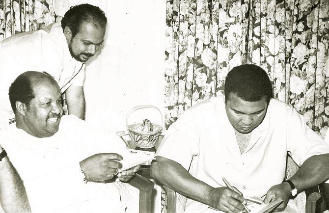 Muhammad Ali (right) signs an autograph for the writer (centre) as Ali’s aide Jabir Mohammed looks on in Madras, 1990. Pic/Gulu Ezekiel 