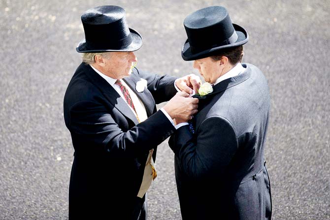 A racegoer adjusts a rosette on another at the Royal Ascot horse racing meet in Ascot, west of London, recently. Pic/AFP