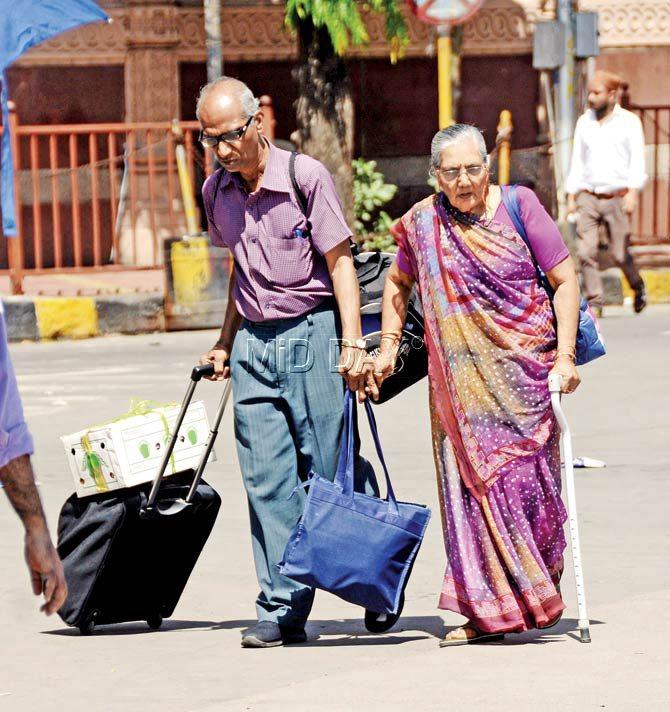An elderly couple trudges along with their heavy bags in search of a taxi outside Dadar station yesterday. Pic/Pradeep Dhivar
