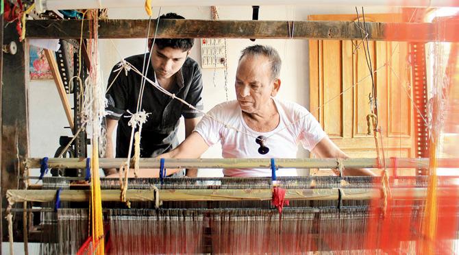 A young worker learns the craft from a senior weaver in a still from the documentary 