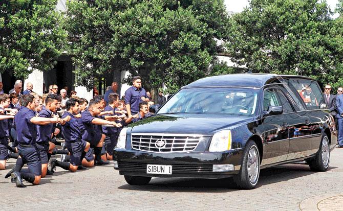 Auckland Grammar students perform a haka in tribute as the hearse passes by