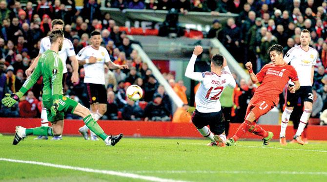 Liverpool-s Roberto Firmino in red shoots past Manchester United goalkeeper David de Gea left to score his team’s second goal during their UEFA Europa League Round-of-16 first leg tie at Anfield in Liverpool on Thursday. Daniel Sturridge scored the first goal for Liverpool, who won 2-0. Pic/AFP