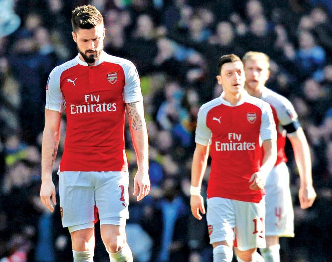 A stunned Arsenal striker Olivier Giroud and midfielder Mesut Ozil (right) prepare for the restart after conceding the first goal against Watford in the FA Cup quarter-final at Emirates Stadium in London yesterday