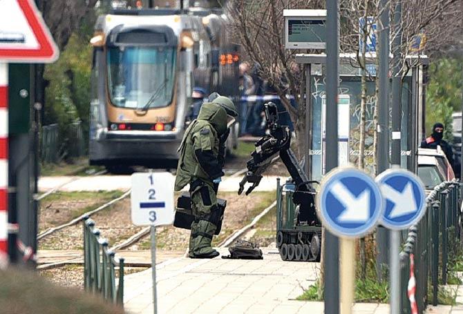 A bomb squad agent and a robot stand next to a suspicious object at a tramway station yesterday in Schaerbeek suburb, Brussels. Pic/AFP