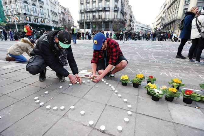 Locals leave candles and flowers in front of the stock exchange building in Brussels in tribute to the victims of the triple bomb attacks that rocked the city yesterday. Pic/AFP