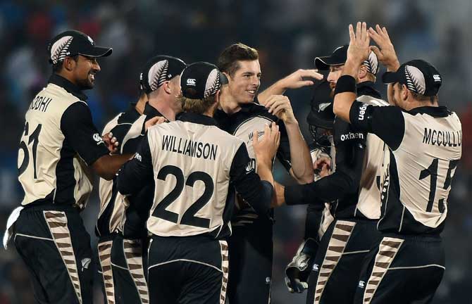 The New Zealand team celebrates the fall of an Indian wicket