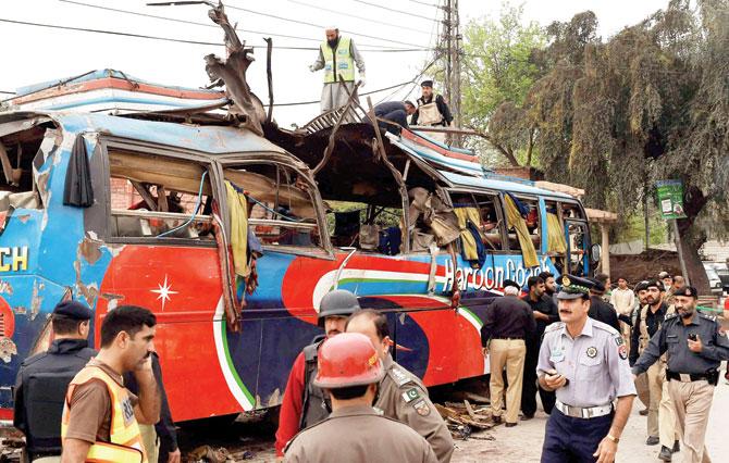 Pakistani volunteers and security forces inspect the bus destroyed after the bomb blast. Pic/AFP