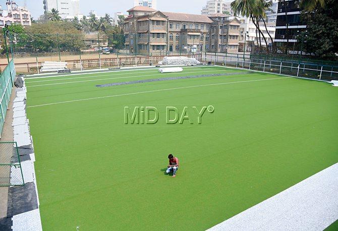 A worker watches over the new artificial turf at St Andrew’s High School in Bandra. pics/suresh karkera