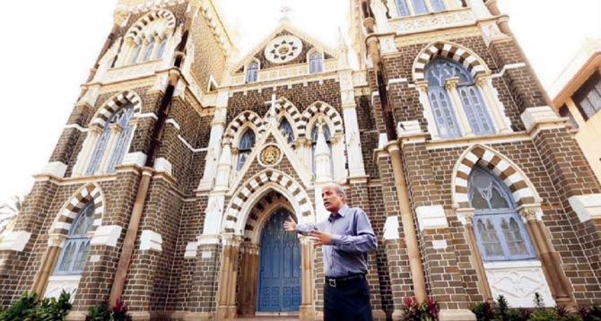 Architect David Cardoz points to the black, cream and brown coloured  walls of the church in  a still  from the documentary