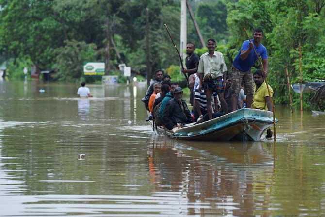 Sri Lankan residents use a boat to travel through floodwaters. Pic/ AFP