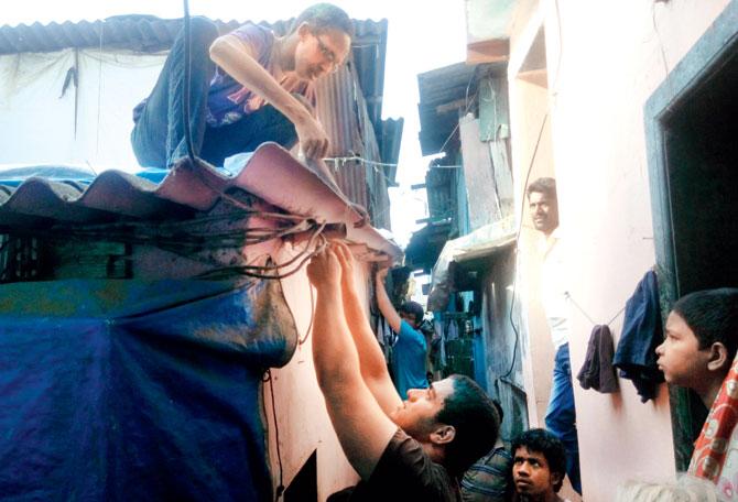 Students adding new roofing material to a house in Dharavi