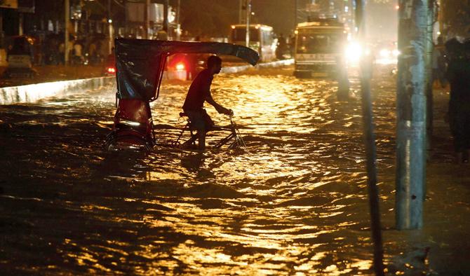A rickshaw puller rides along a water-logged road after a thunder storm in Guwahati on Tuesday. 